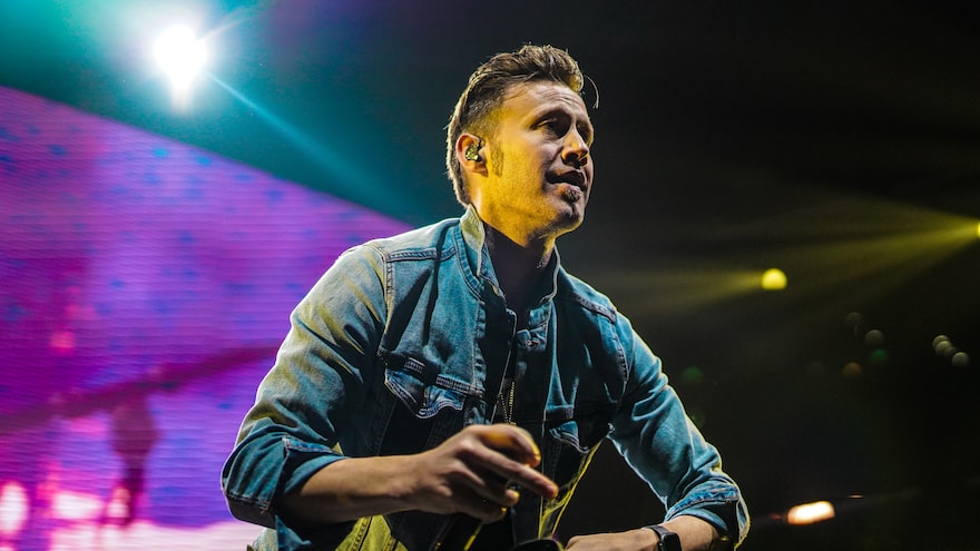 man in blue denim jacket holding microphone