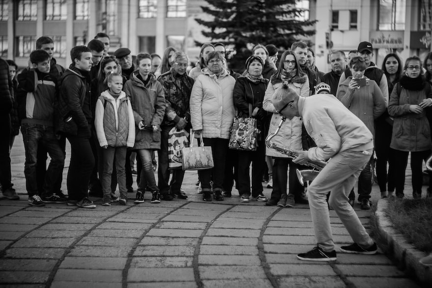 Man playing saxophone in street with crowd